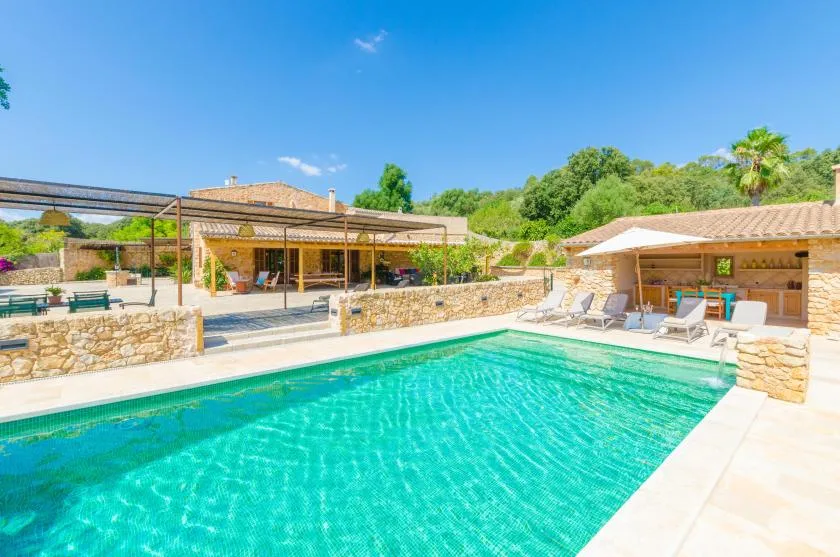 An outdoor swimming pool sits beside a shaded patio and seating area.