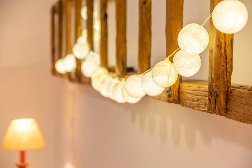 A warmly lit interior wall with a string of glowing round lights and a table lamp.