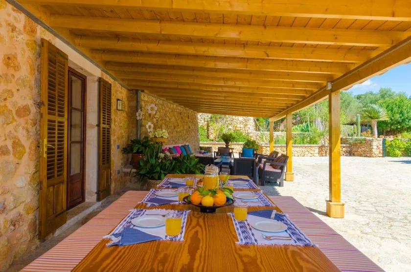 A covered outdoor dining area with a set table and seating.