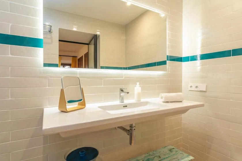 A tiled bathroom vanity with a sink and large wall mirror.