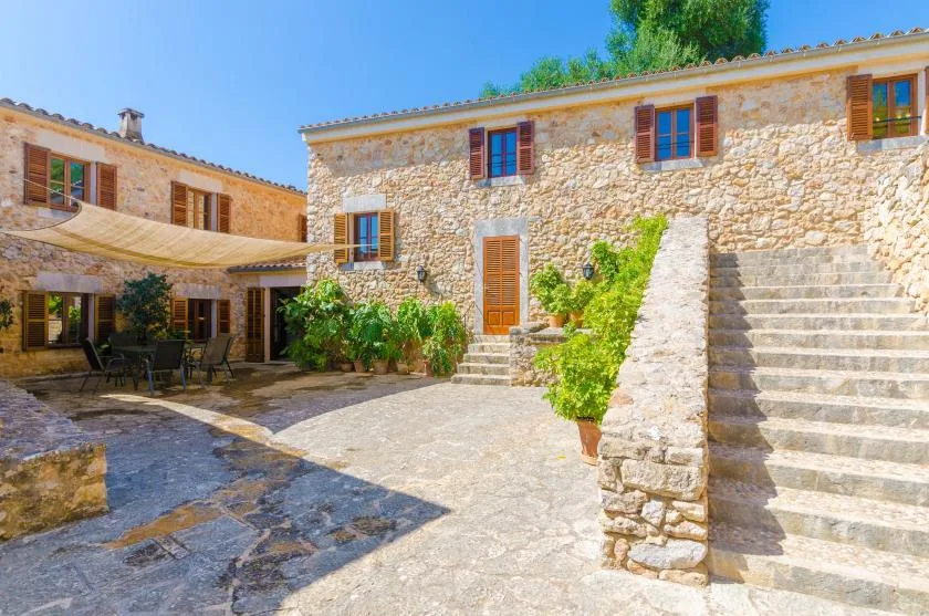 A stone courtyard with a shaded seating area and stairs.