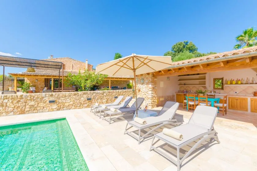A sunny outdoor pool patio with lounge seating and a covered bar area.