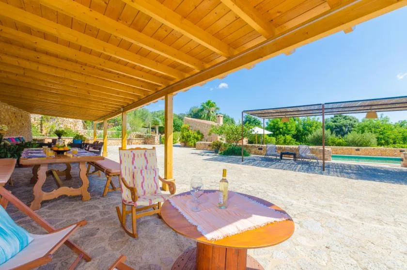 A covered outdoor patio with seating overlooks a pool and landscaped grounds.