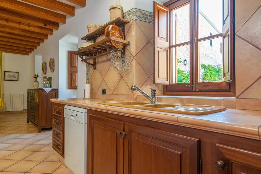 A kitchen with wooden cabinets, a sink, and an open window.