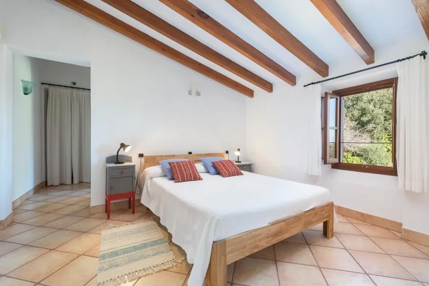 A bedroom with a wooden bed and exposed ceiling beams.