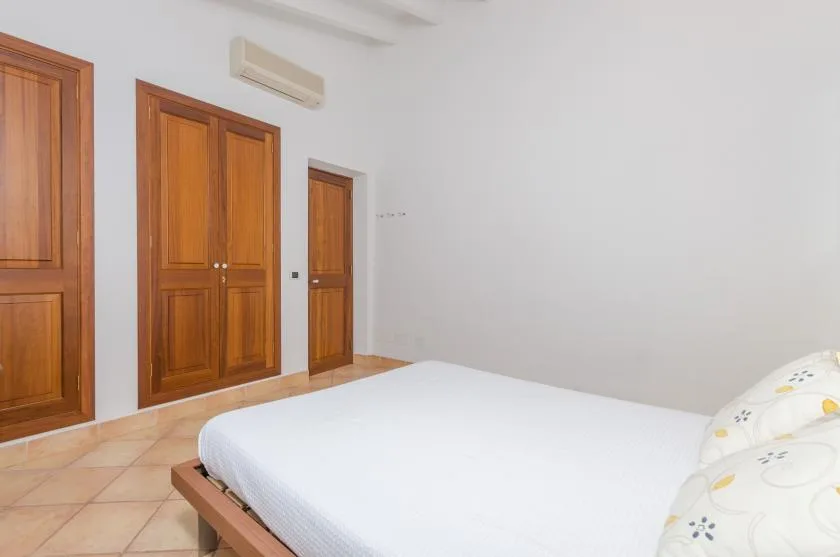 A bedroom with a white bed and wooden doors.