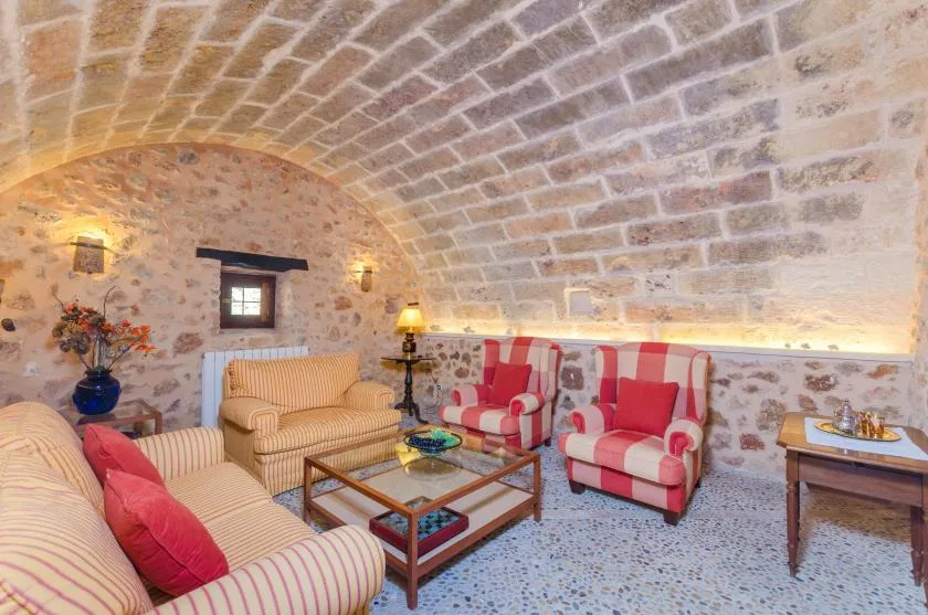 A stone-vaulted living room with striped seating and a glass coffee table.