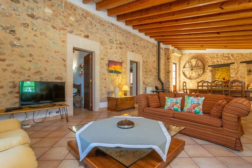 A living room with seating, a television, and exposed wooden ceiling beams.