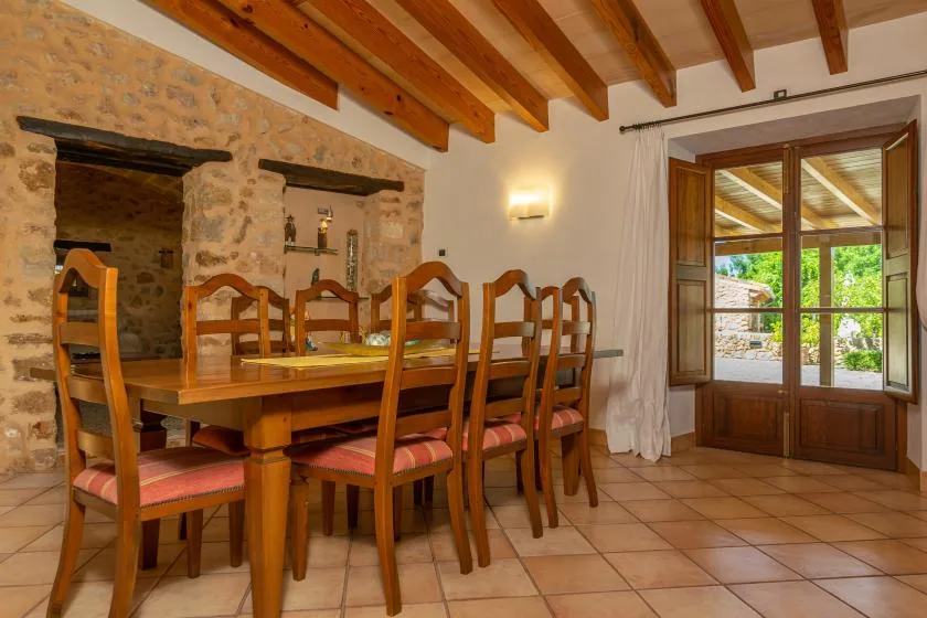 A dining area with a wooden table and chairs beside a glass-paned door.