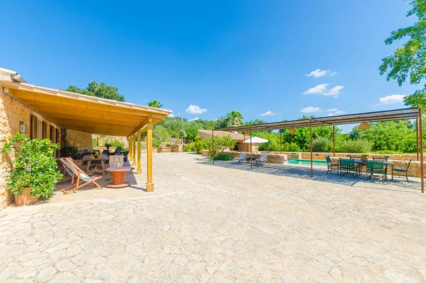 A sunny outdoor patio with covered seating, a pool, and dining tables.