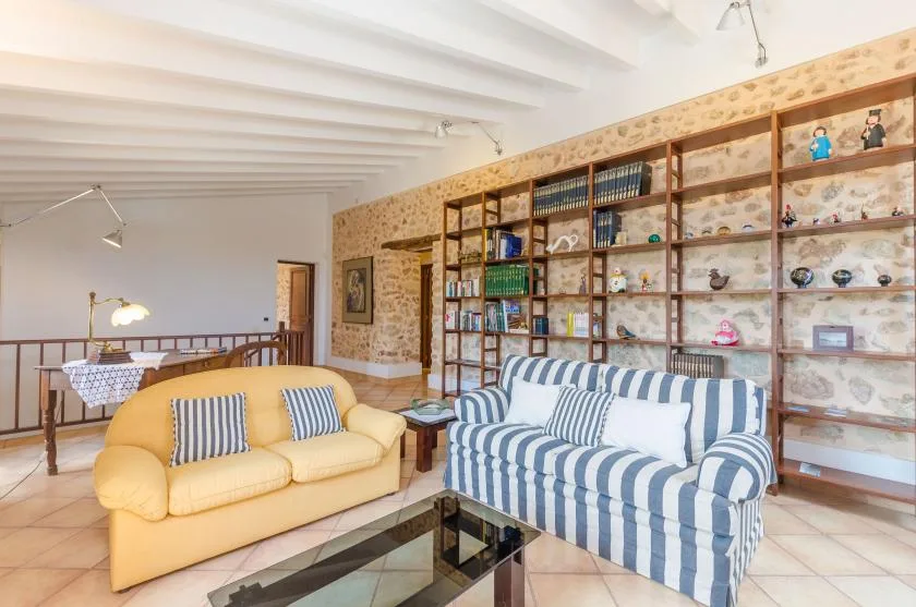 A living room with yellow and blue striped seating beside a wall of bookshelves.