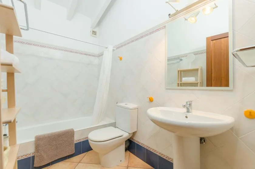A bright bathroom with a sink, toilet, and shower curtain.