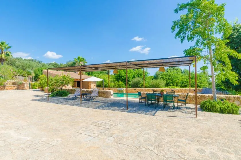 An outdoor patio with a shaded dining area beside a swimming pool.