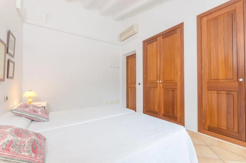 A bedroom with a white bed and several wooden doors.