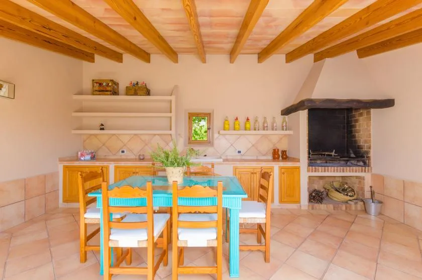 A rustic kitchen and dining area with a wooden table beneath exposed ceiling beams.