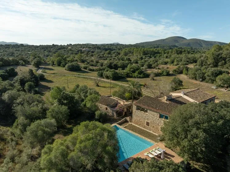Aerial view of a countryside property with a swimming pool and wooded hills.