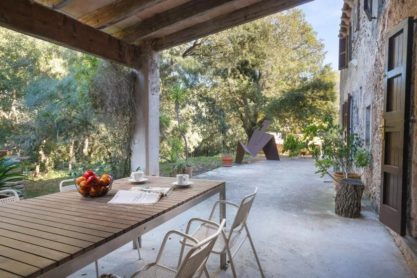 A covered outdoor dining area with a wooden table and garden views.