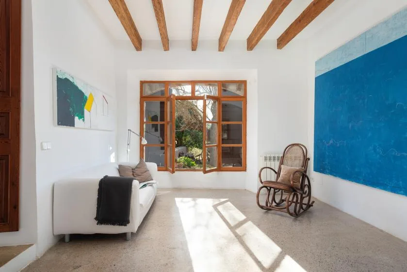 A bright living room with white seating, a blue wall, and exposed ceiling beams.