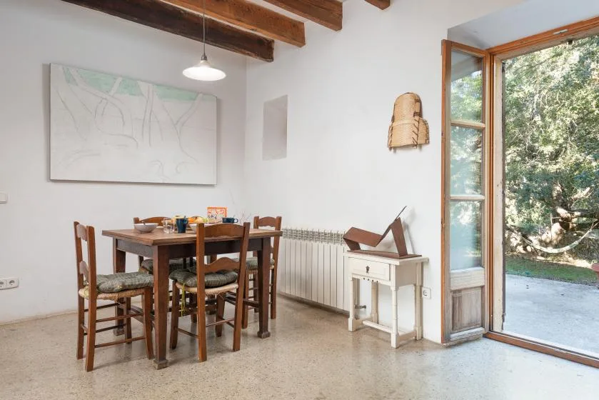 A dining area with a wooden table and chairs beside an open glass door.