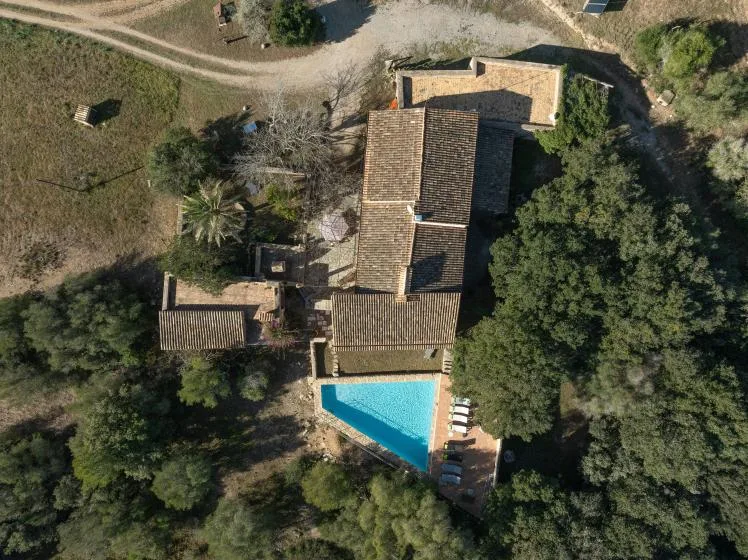 An aerial view of a tiled-roof building beside a small swimming pool.