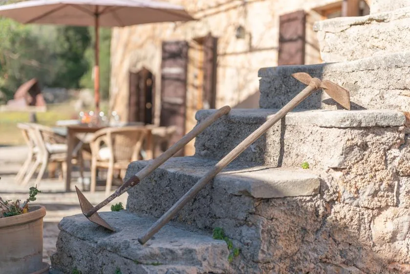 Stone steps lead to a rustic courtyard with outdoor tables and chairs.