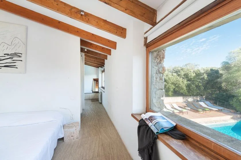 A bright bedroom opens onto a poolside view through a large window.
