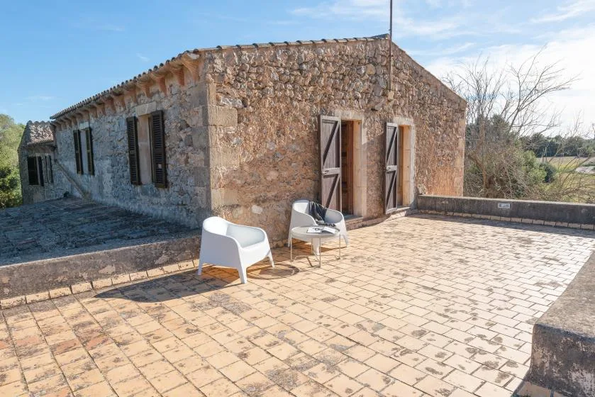 Stone building beside a paved terrace with outdoor seating.