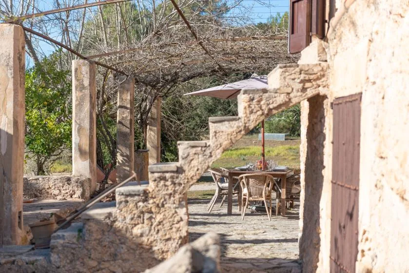 A stone terrace with outdoor seating beneath a vine-covered pergola.