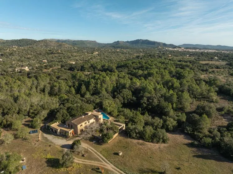 Aerial view of a country house surrounded by wooded countryside.