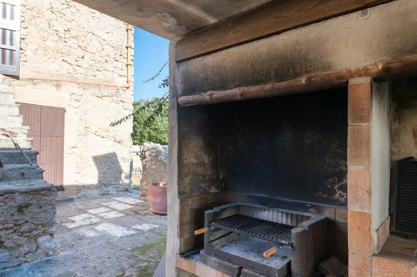 An outdoor stone barbecue area with a large built-in grill.
