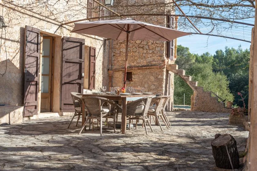 A stone patio with outdoor seating beneath a large umbrella.