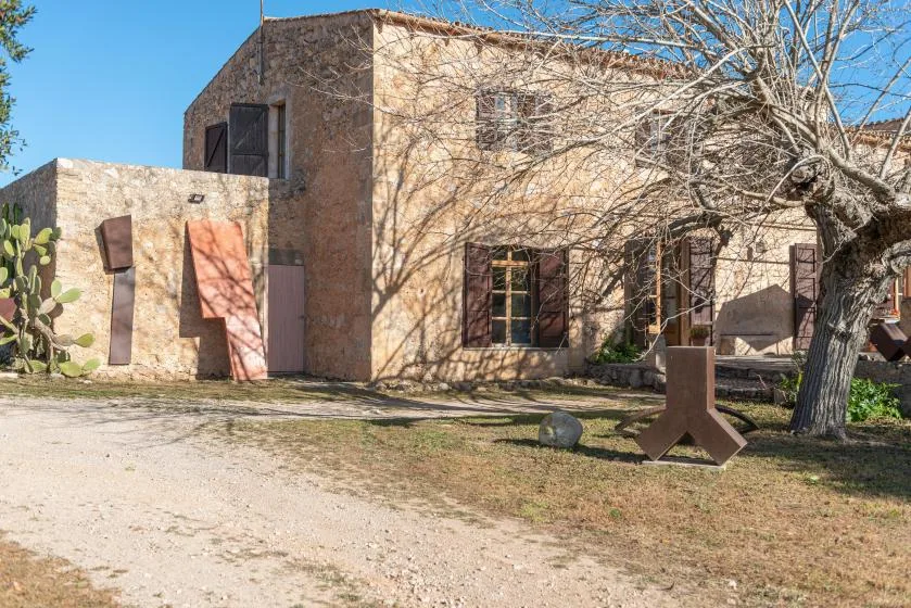 A stone building stands beside a bare tree and a gravel path.