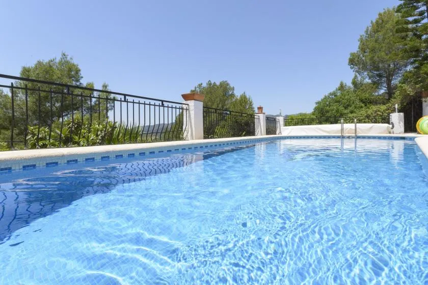 A swimming pool with clear blue water and a metal railing along the edge.
