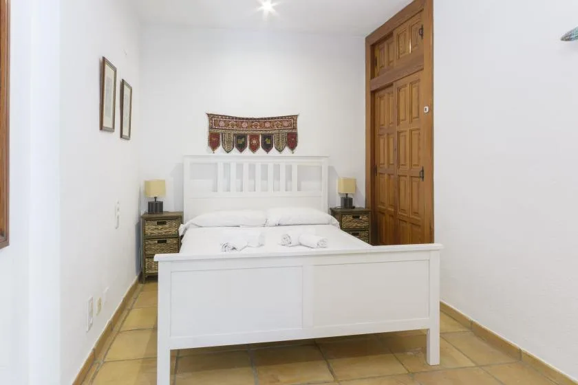 A bedroom with a white bed, bedside tables, and a wooden door.