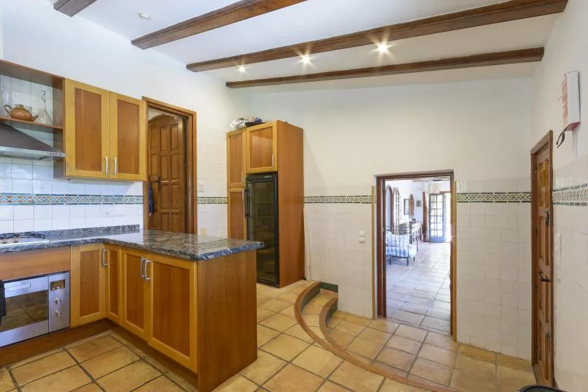 A kitchen with wooden cabinetry and a tiled floor opens onto a dining area.