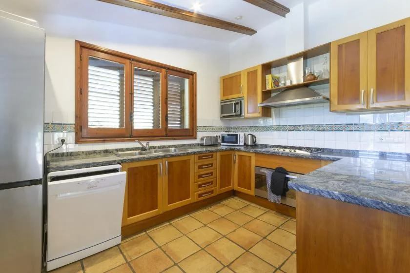 A kitchen with wooden cabinets, tiled flooring, and a large countertop.