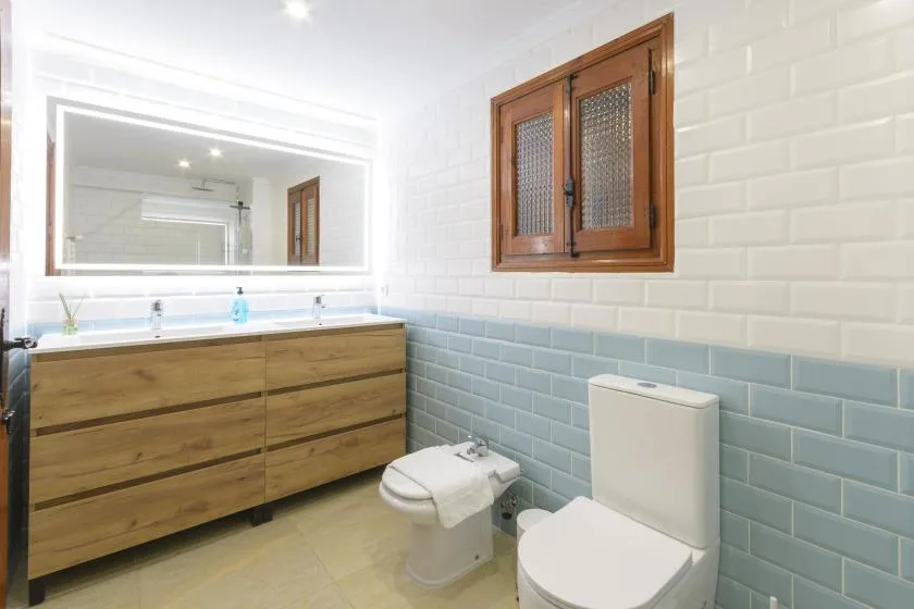 A bathroom with a wood vanity, wall mirror, and toilet.