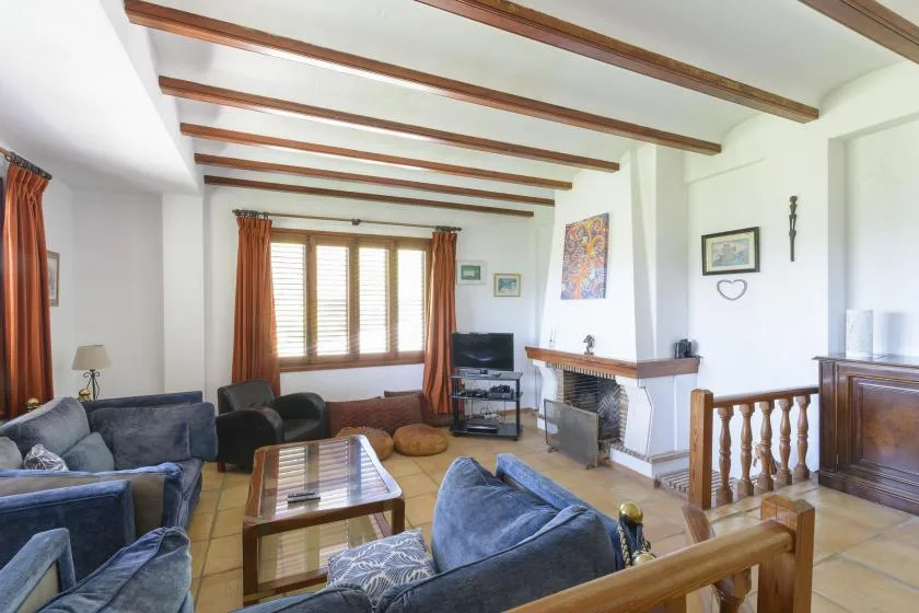 A living room with seating, a fireplace, and wooden ceiling beams.