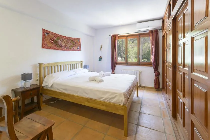A bedroom with a double bed, wooden wardrobes, and a window.