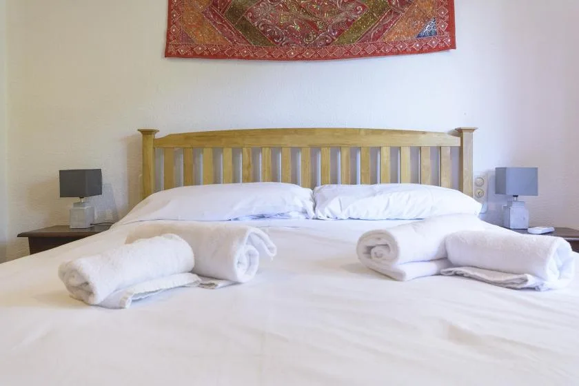 A bedroom with a neatly made bed and rolled towels.