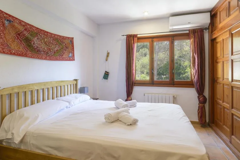 A bedroom with a neatly made bed beneath a window.