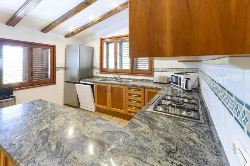 A kitchen with wooden cabinets, a stone countertop, and a gas cooktop.