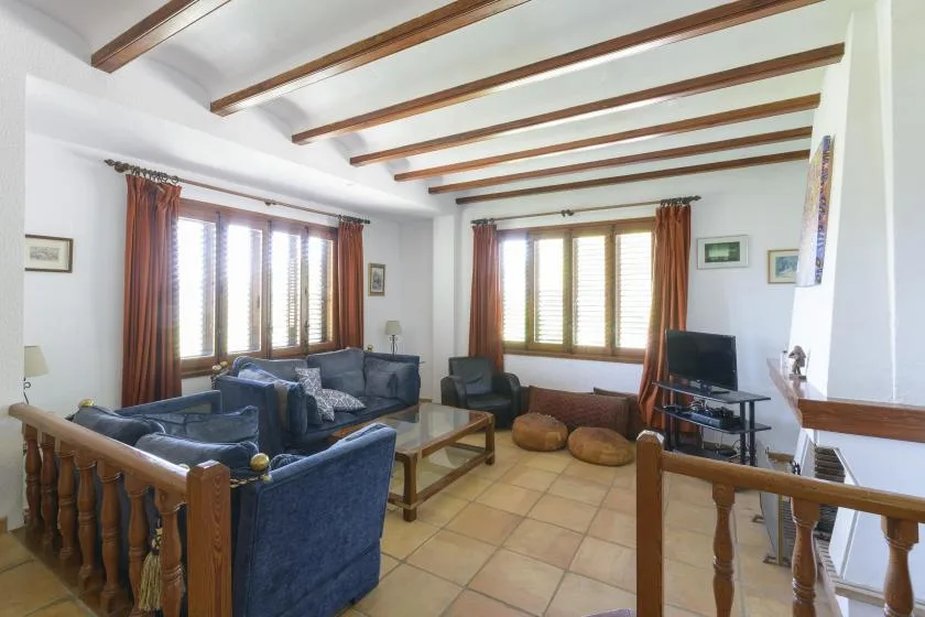 A living room with seating, a coffee table, and windows with wooden blinds.