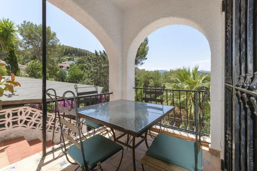 A covered terrace with arched openings, a glass-topped table, and outdoor seating.