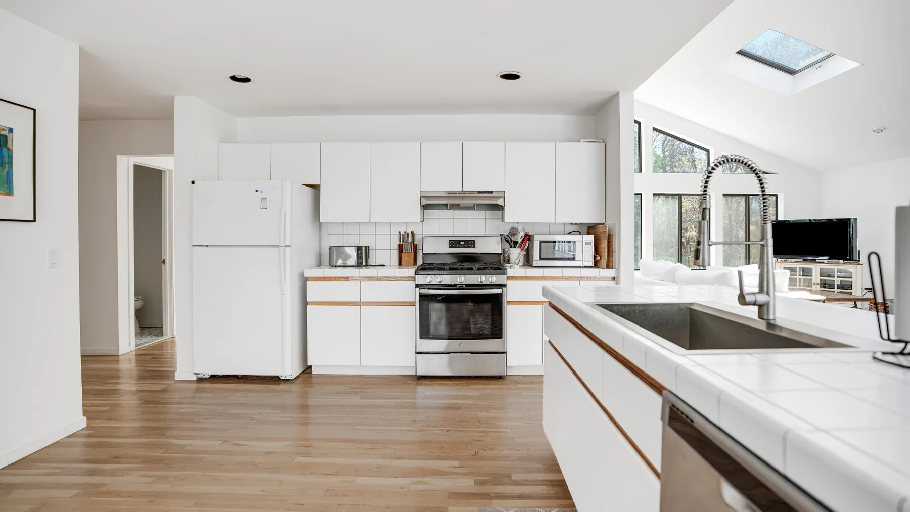 Una cocina luminosa con gabinetes blancos, electrodomésticos de acero inoxidable y una isla grande.