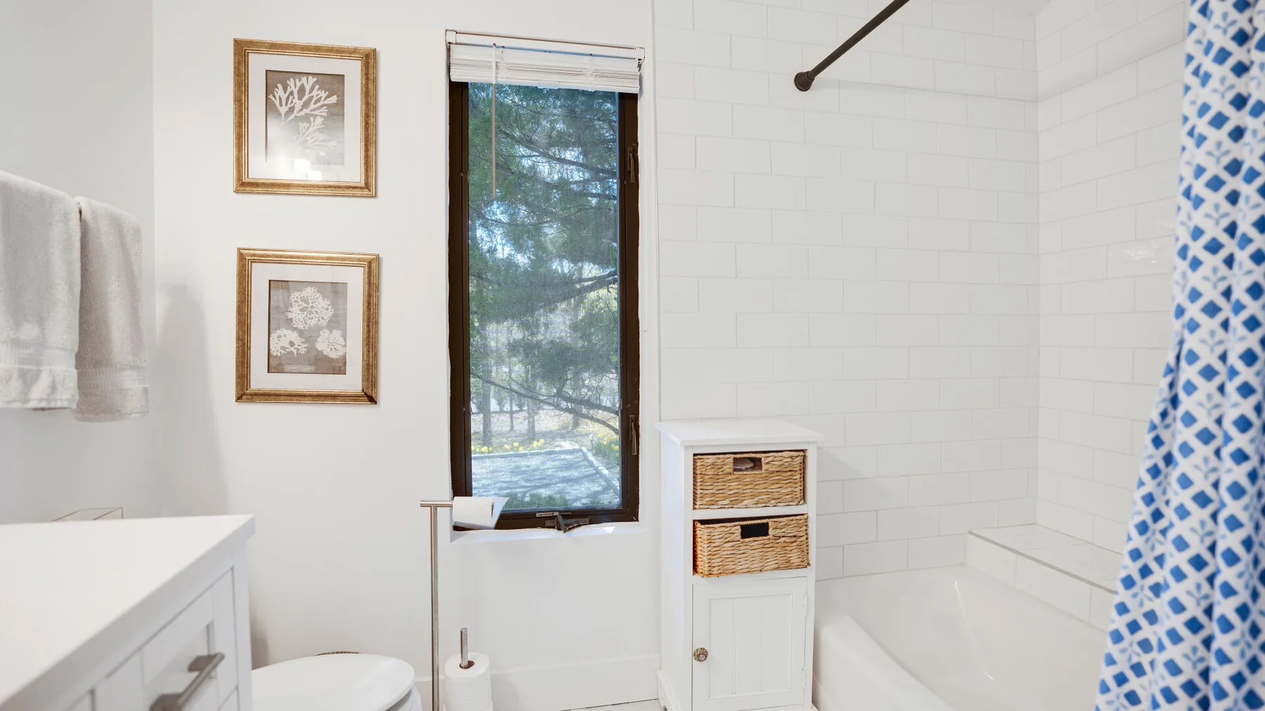Un baño luminoso con bañera, cortina de ducha estampada y ventana.