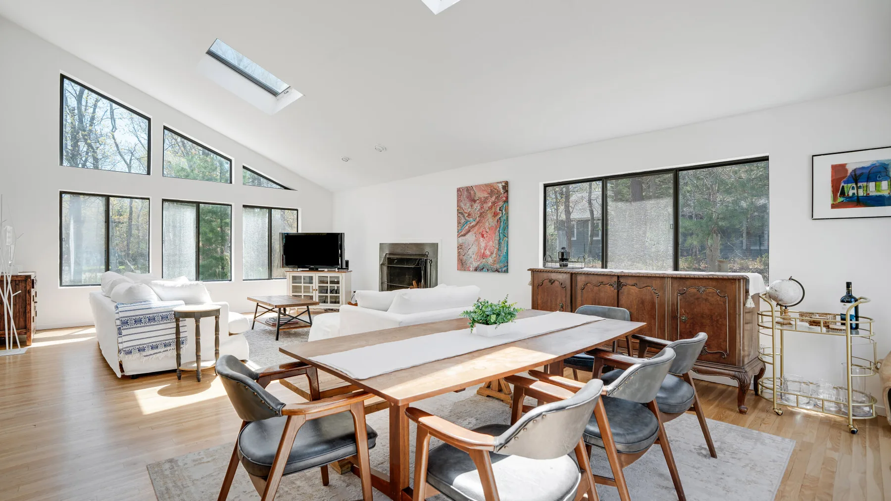 Una sala luminosa con una mesa de comedor y asientos junto a grandes ventanas.