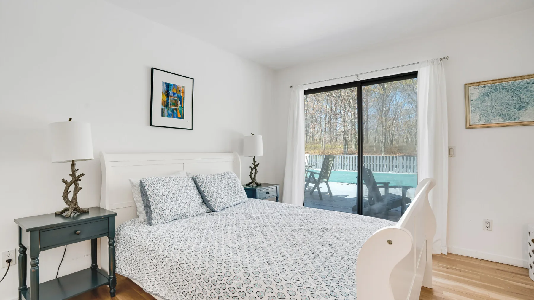 Un dormitorio luminoso con una cama tendida junto a puertas corredizas de vidrio que dan a una terraza.
