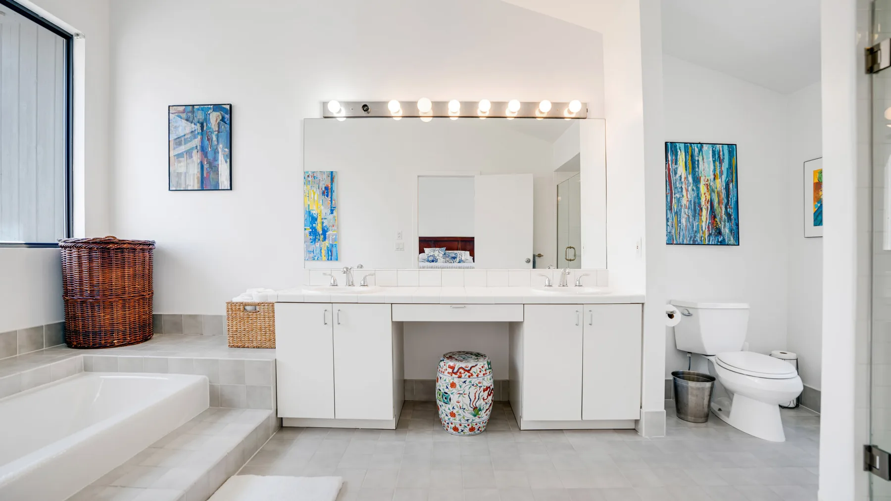 Un baño luminoso con un lavabo largo, un espejo grande y una bañera.