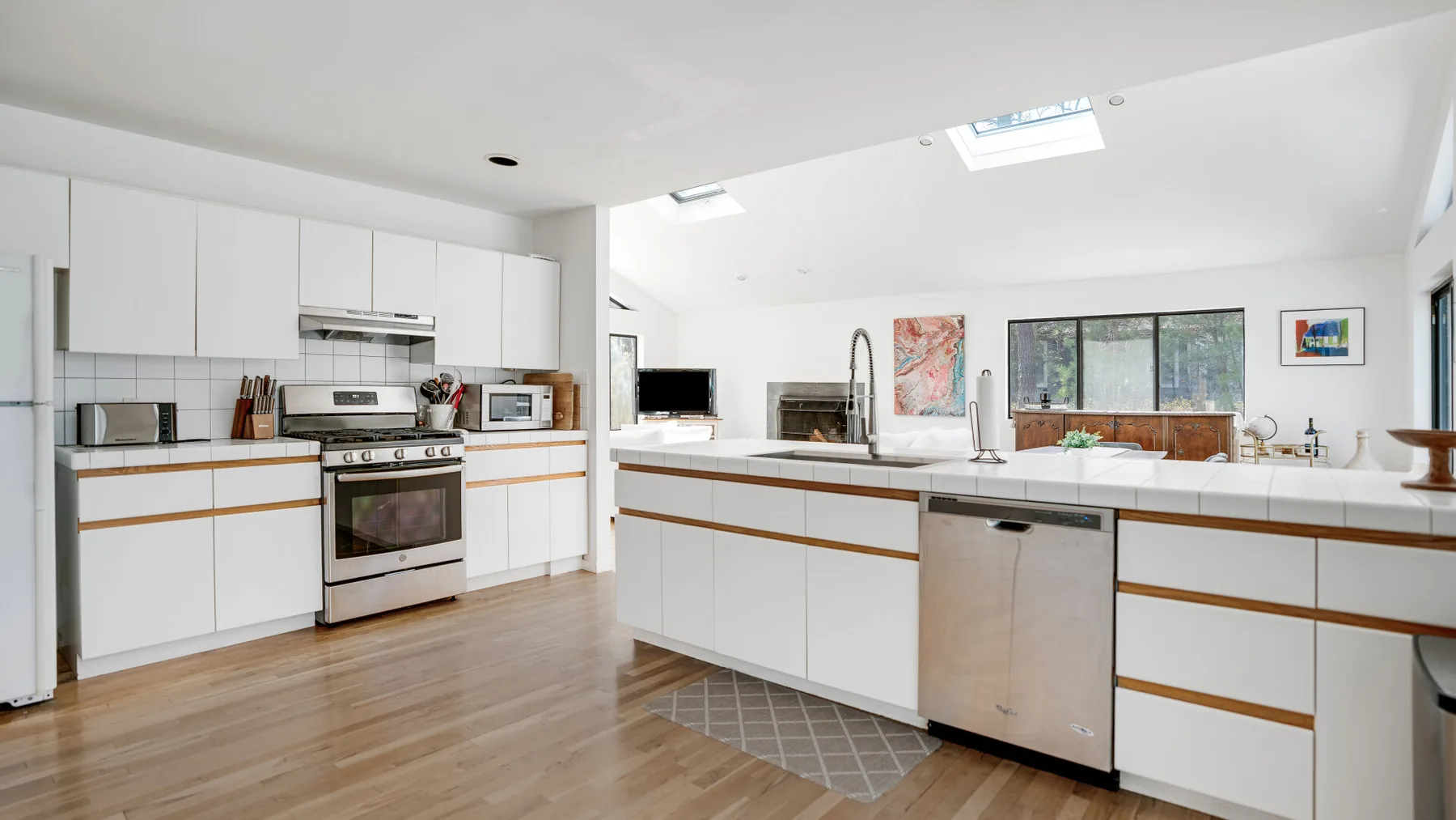 Una cocina luminosa con gabinetes blancos, una isla central y tragaluces.